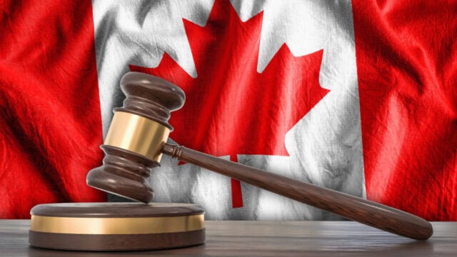 Wooden gavel on a sounding block in front of a red maple-leaf flag