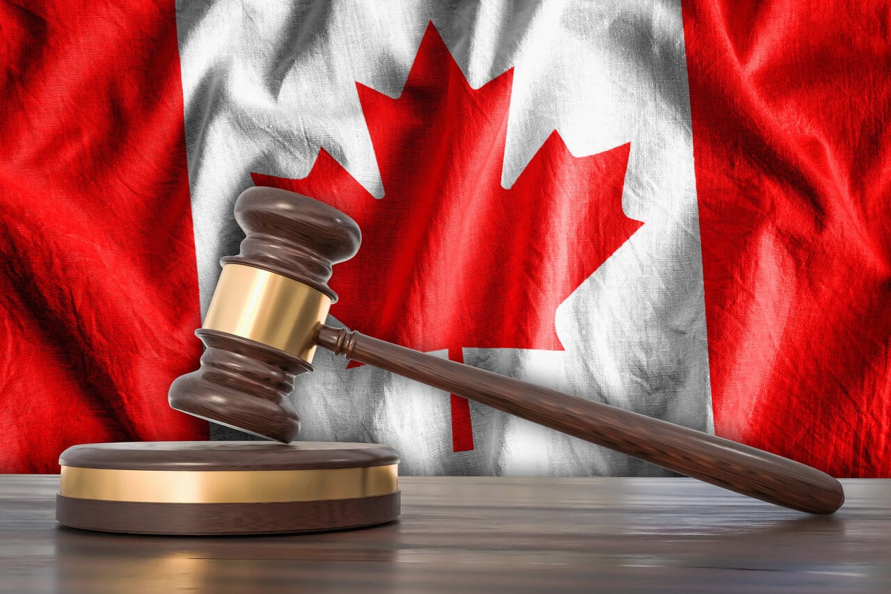 Wooden gavel on a sounding block in front of a red maple-leaf flag
