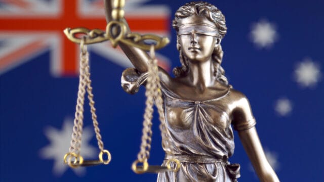 Lady Justice statuette holding scales against a starred flag backdrop