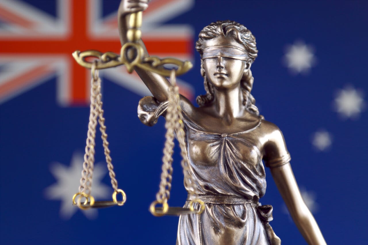 Lady Justice statuette holding scales against a starred flag backdrop