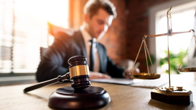 Young lawyer working at a warm sunlit office desk with a gavel and brass scale