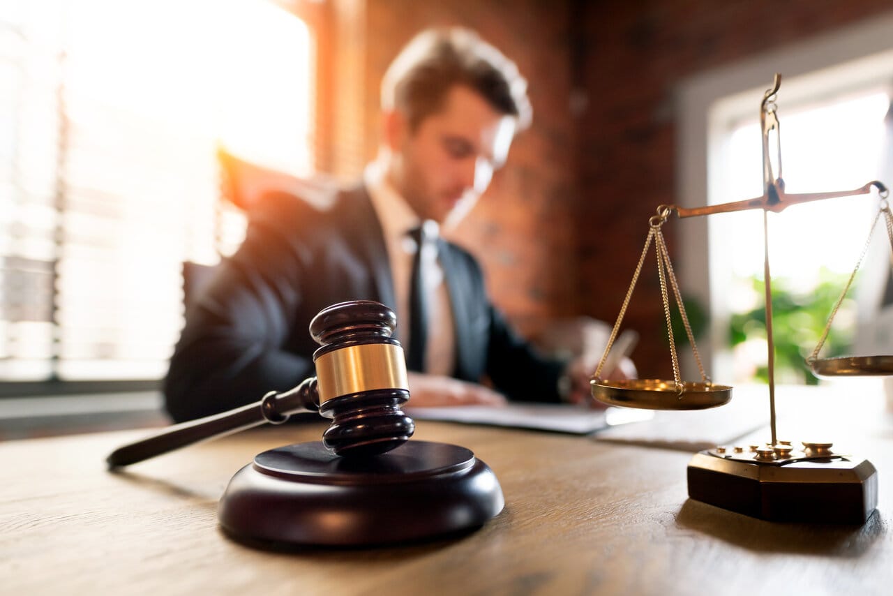 Young lawyer working at a warm sunlit office desk with a gavel and brass scale
